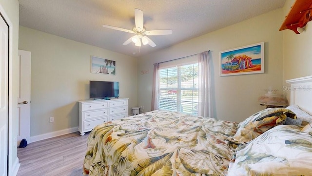 bedroom featuring ceiling fan, light hardwood / wood-style floors, and a textured ceiling