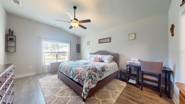 bedroom with hardwood / wood-style floors, a textured ceiling, ceiling fan, and lofted ceiling