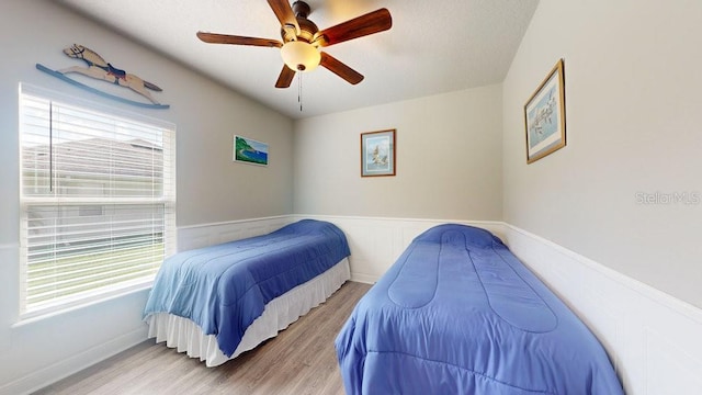 bedroom with ceiling fan, light wood-type flooring, and multiple windows