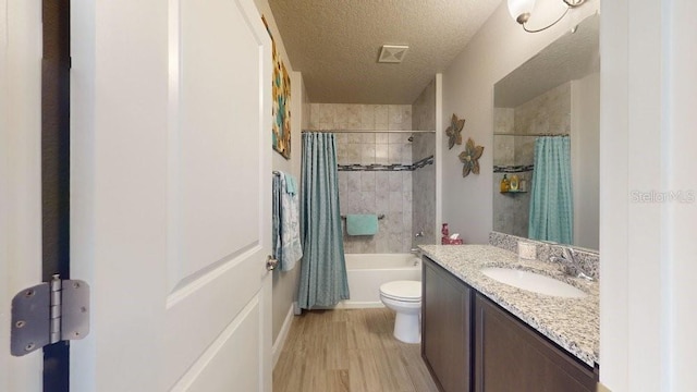 full bathroom featuring wood-type flooring, a textured ceiling, toilet, vanity, and shower / tub combo