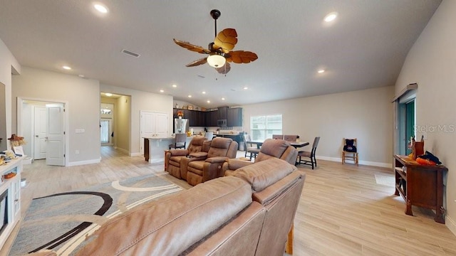 living room with light wood-type flooring, ceiling fan, and lofted ceiling