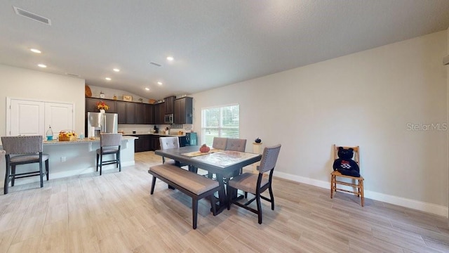 dining space featuring light hardwood / wood-style flooring and lofted ceiling