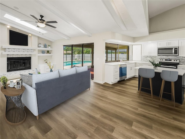 living room featuring lofted ceiling with beams, dark hardwood / wood-style floors, ceiling fan, and sink