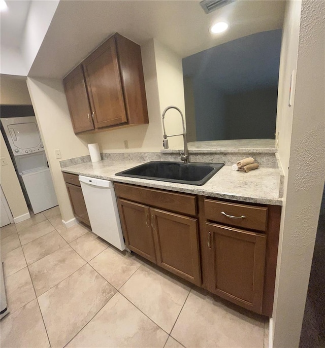 kitchen with dishwasher, light tile patterned flooring, a sink, and stacked washer and clothes dryer