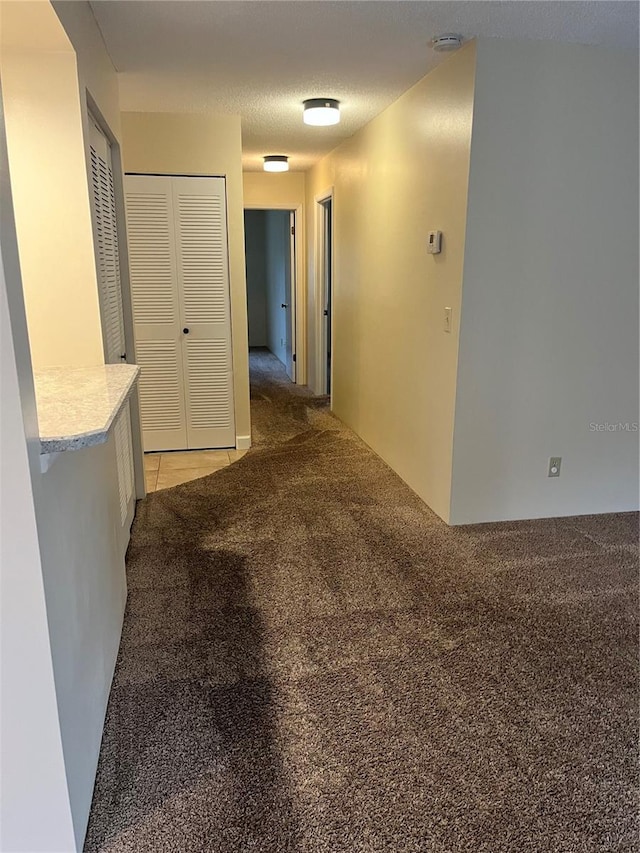 corridor with a textured ceiling and light colored carpet