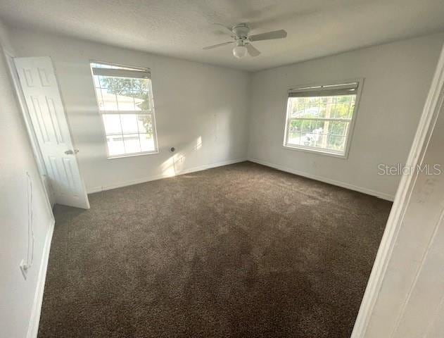 unfurnished room featuring ceiling fan and dark carpet