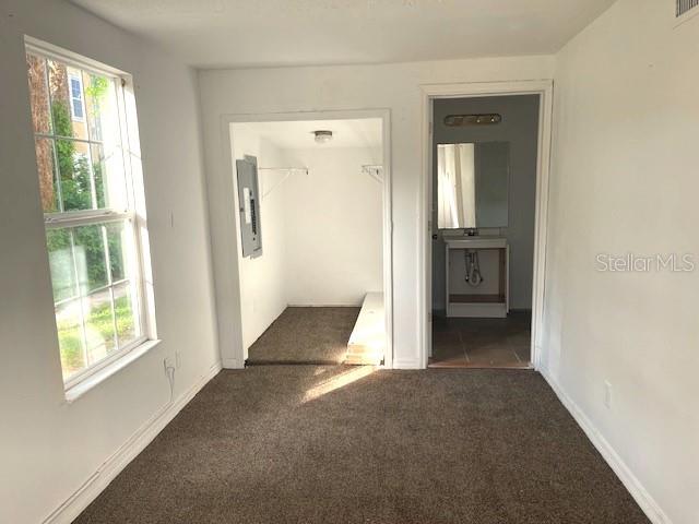 hallway with dark carpet and electric panel