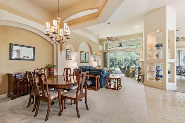 carpeted dining space featuring ceiling fan with notable chandelier and built in shelves