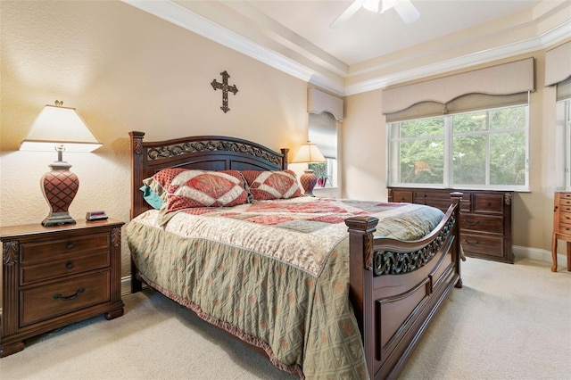 bedroom featuring ceiling fan, crown molding, light colored carpet, and a tray ceiling