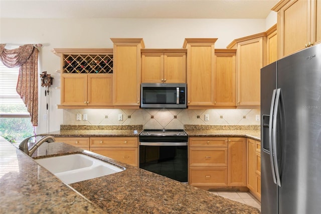 kitchen featuring appliances with stainless steel finishes, dark stone countertops, sink, backsplash, and light tile patterned flooring