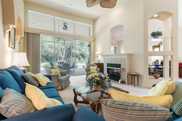 living room with ceiling fan, a high ceiling, light carpet, and a fireplace