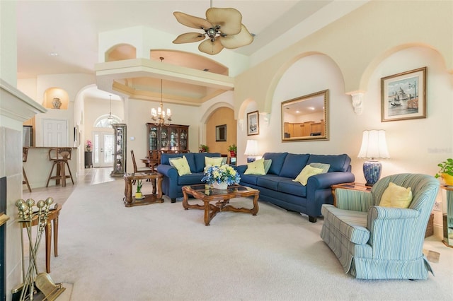 living room featuring ceiling fan with notable chandelier, a high ceiling, and light carpet