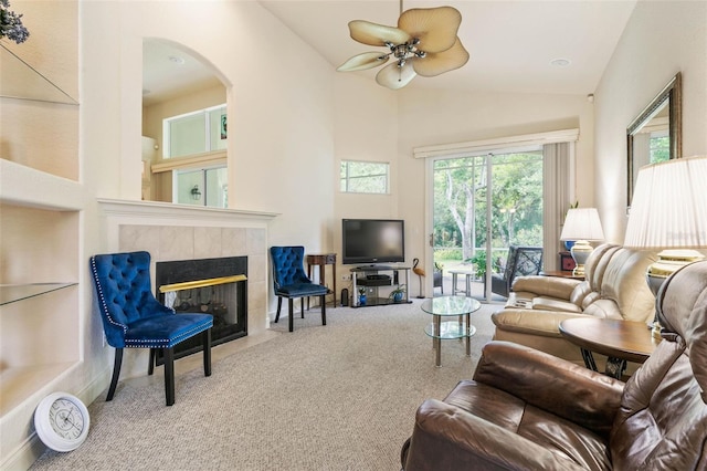 carpeted living room with vaulted ceiling, ceiling fan, and a tiled fireplace