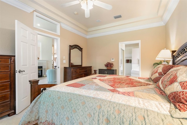 bedroom featuring ceiling fan, ensuite bath, crown molding, and light colored carpet