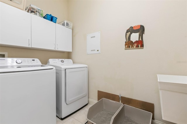 laundry area with light tile patterned floors, washing machine and clothes dryer, and cabinets