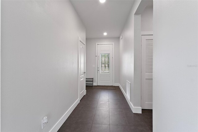 hall with dark tile flooring