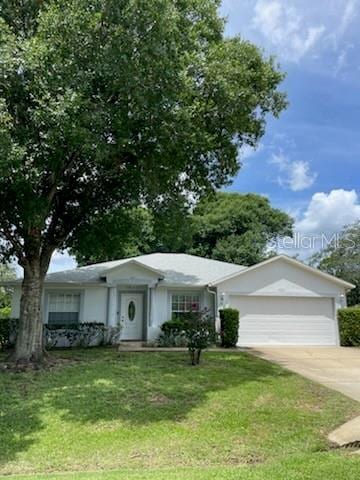 single story home featuring driveway, a front lawn, and an attached garage