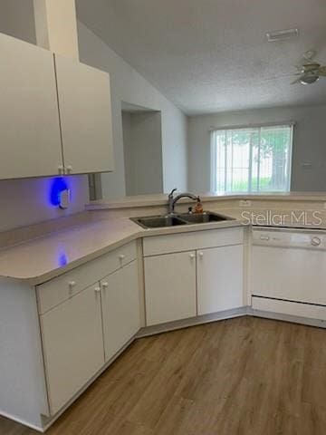 kitchen with white dishwasher, light countertops, light wood-style floors, white cabinetry, and a sink