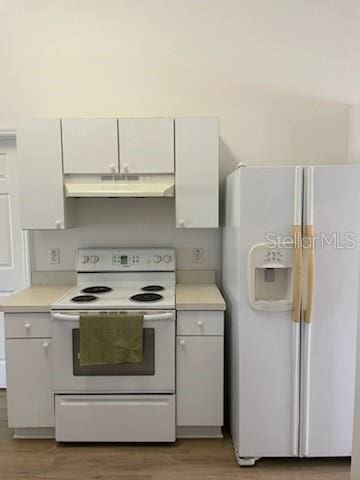 kitchen featuring under cabinet range hood, white appliances, wood finished floors, white cabinets, and light countertops