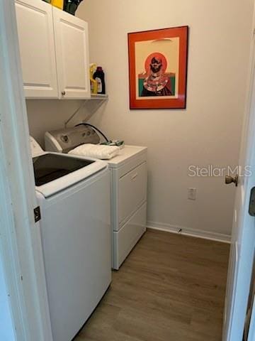 washroom featuring wood finished floors, cabinet space, baseboards, and separate washer and dryer