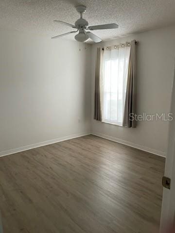 spare room with dark wood-style floors, a textured ceiling, and baseboards