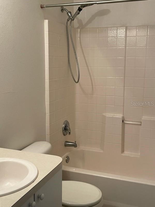 full bathroom featuring tiled shower / bath, vanity, and toilet