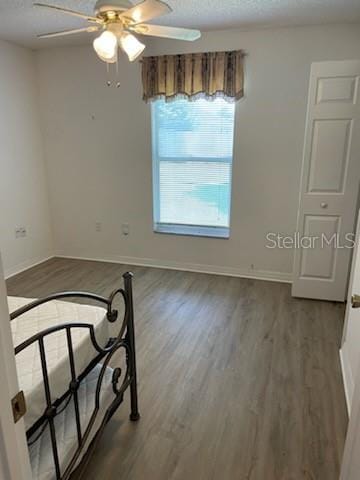 spare room with ceiling fan, a textured ceiling, baseboards, and wood finished floors