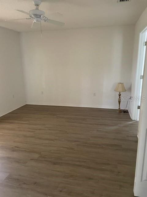 empty room with visible vents, dark wood finished floors, and a ceiling fan