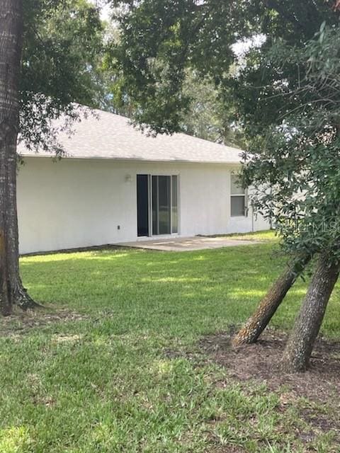 rear view of house with a yard, a patio, and stucco siding