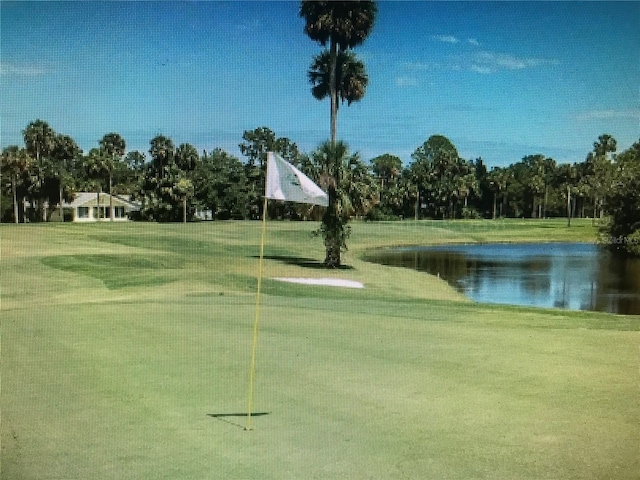 view of home's community with view of golf course, a yard, and a water view