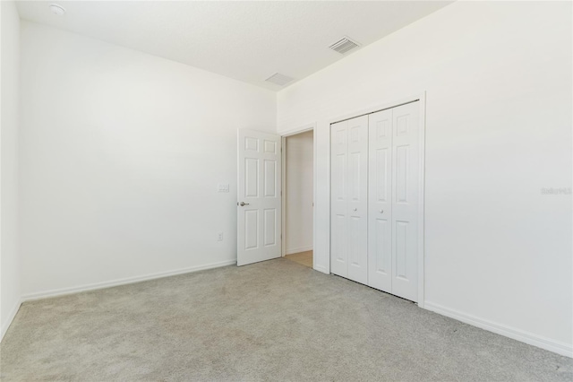 unfurnished bedroom featuring light carpet and a closet