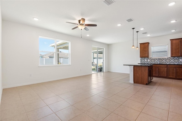 kitchen featuring a center island, hanging light fixtures, ceiling fan, light tile patterned floors, and tasteful backsplash