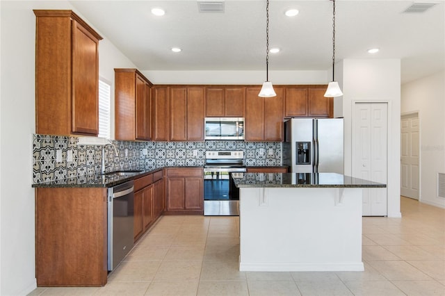 kitchen with dark stone countertops, sink, a center island, and appliances with stainless steel finishes