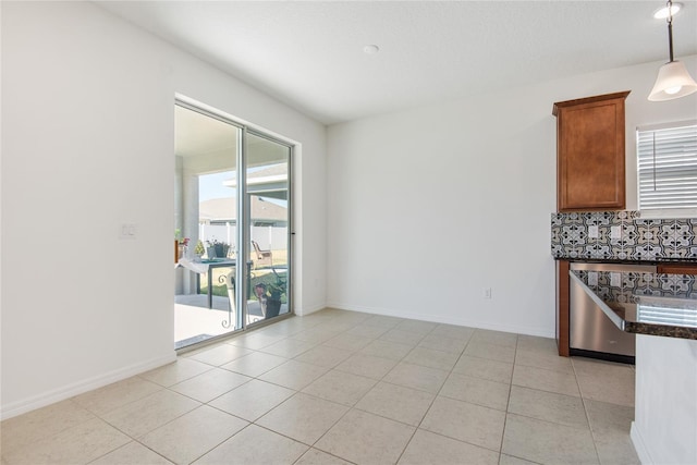 kitchen featuring decorative backsplash, light tile patterned flooring, hanging light fixtures, and stainless steel dishwasher