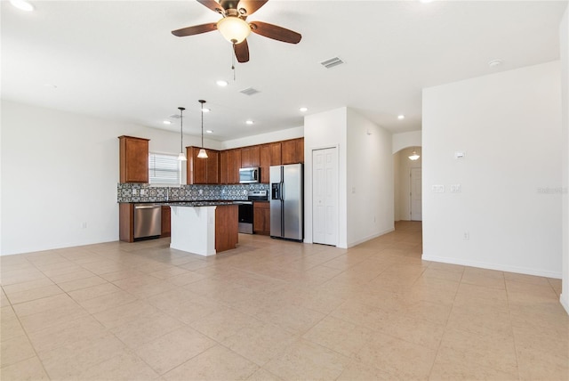 kitchen with appliances with stainless steel finishes, tasteful backsplash, ceiling fan, decorative light fixtures, and a kitchen island