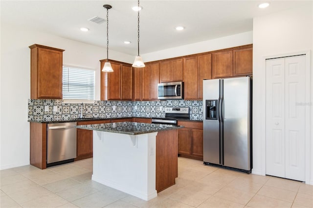 kitchen with backsplash, stainless steel appliances, pendant lighting, dark stone countertops, and a kitchen island