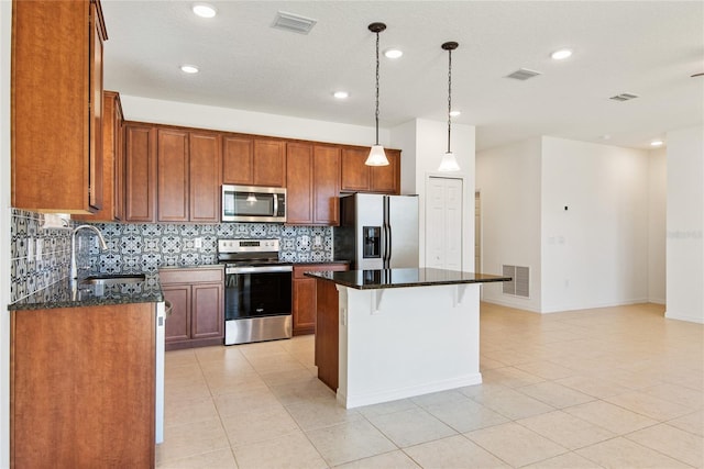 kitchen featuring stainless steel appliances, a kitchen island, dark stone countertops, and sink