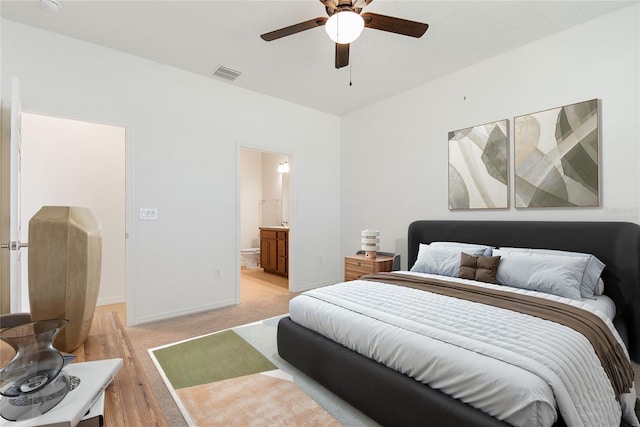 bedroom featuring ceiling fan, ensuite bathroom, and light carpet