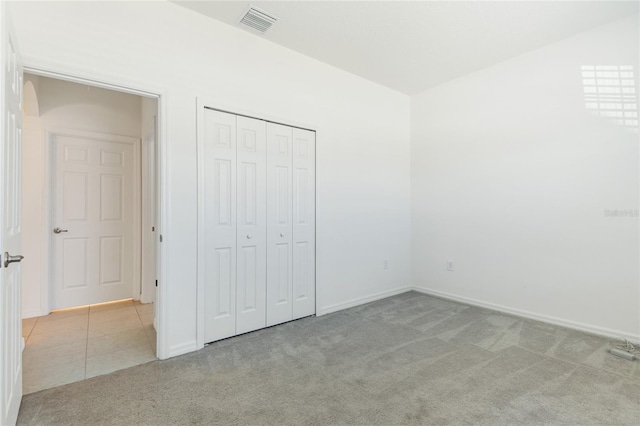 unfurnished bedroom featuring light colored carpet and a closet