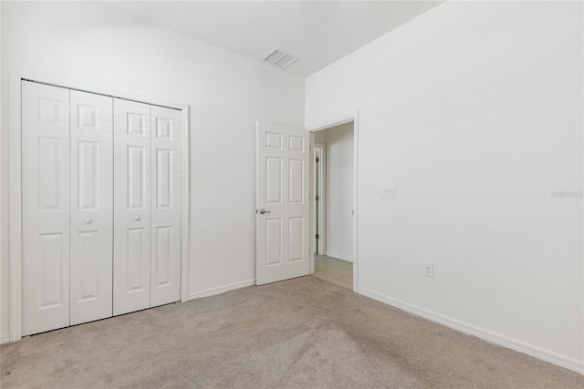 unfurnished bedroom with a closet and light colored carpet