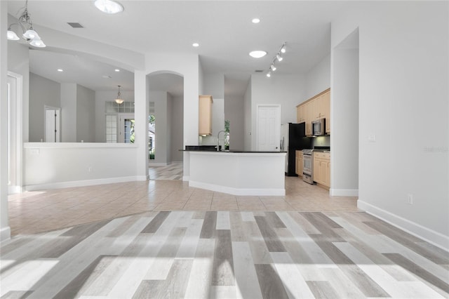 kitchen with sink, light brown cabinets, stainless steel appliances, a notable chandelier, and pendant lighting