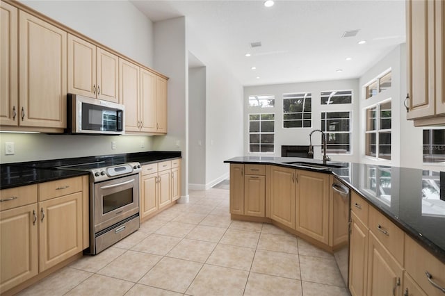 kitchen featuring dark stone countertops, sink, light brown cabinets, and appliances with stainless steel finishes