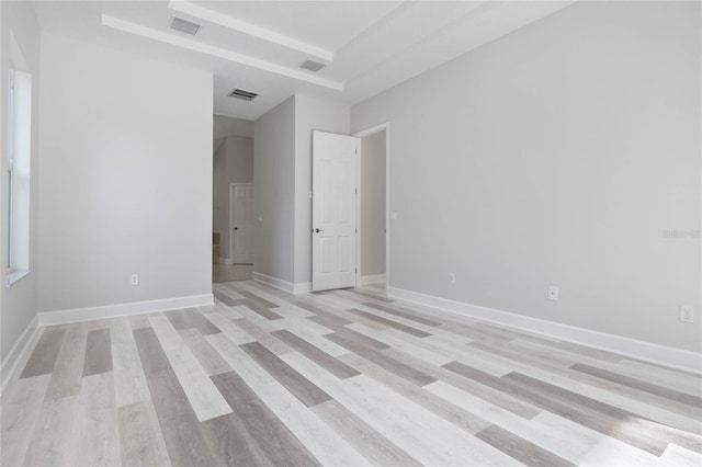 unfurnished room featuring light hardwood / wood-style floors and a tray ceiling