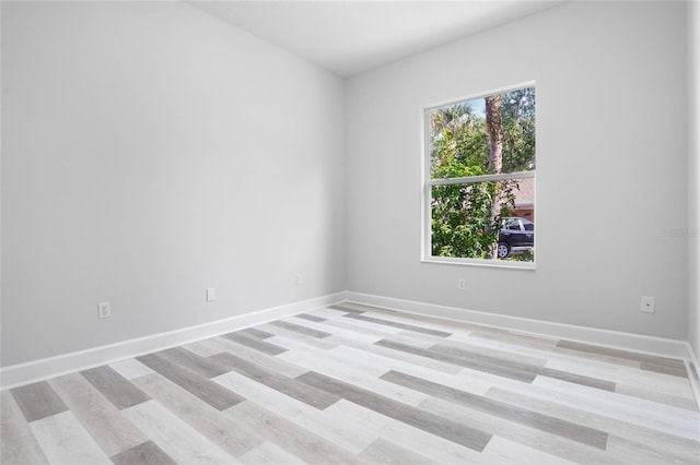 spare room featuring light wood-type flooring and baseboards