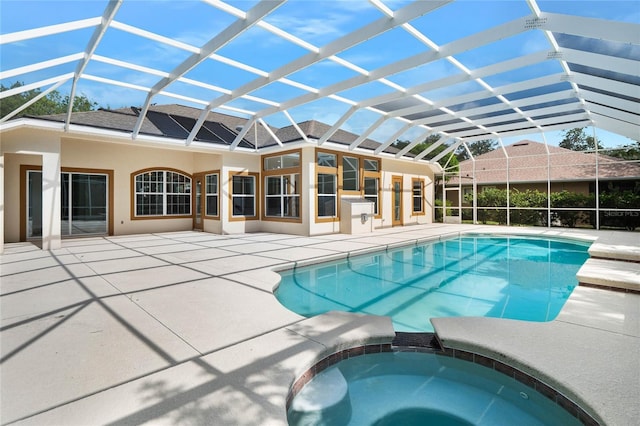 view of pool with glass enclosure, a patio area, and a pool with connected hot tub