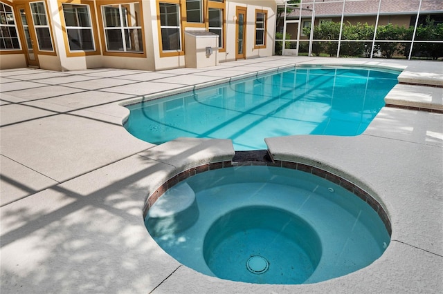 view of pool featuring glass enclosure, a patio area, and a pool with connected hot tub