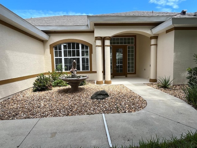 property entrance with roof with shingles, french doors, and stucco siding