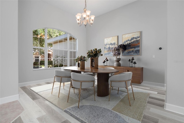 dining room featuring light wood-style floors, a notable chandelier, and baseboards