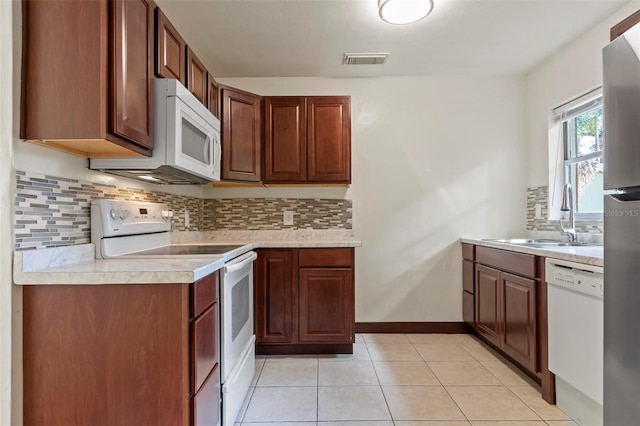 kitchen with decorative backsplash, sink, light tile patterned flooring, and white appliances