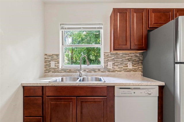 kitchen featuring decorative backsplash, stainless steel fridge, sink, and white dishwasher